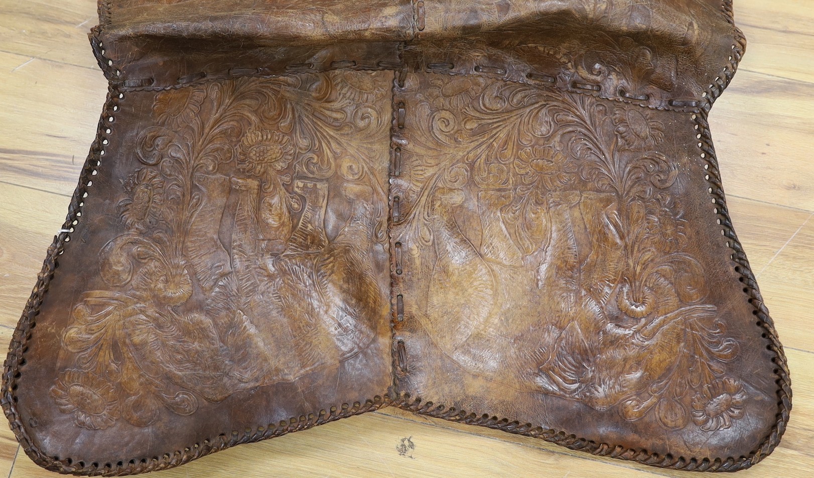 A shaped embossed leather chair seat, with leather thong edging